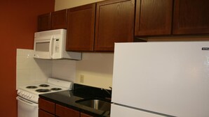 Una cocina con armarios de madera, una estufa blanca, un microondas y un refrigerador.