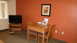 Una habitación con una mesa y sillas de madera, un televisor y un cuadro en la pared.