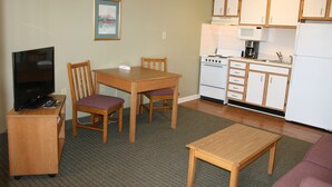 Un espacio habitable compacto con kitchenette, comedor, televisión y sofá.