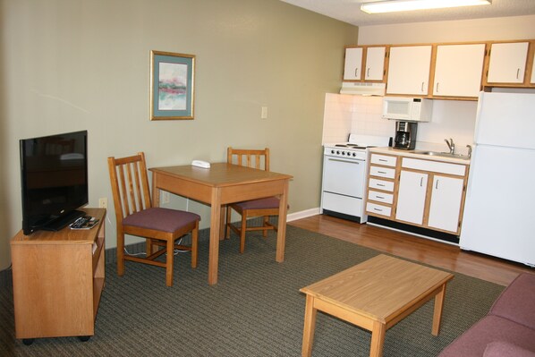 A compact living space with a kitchenette, a dining area, a television, and a sofa. - Affordable Suites Sumter SC (Sumter)
