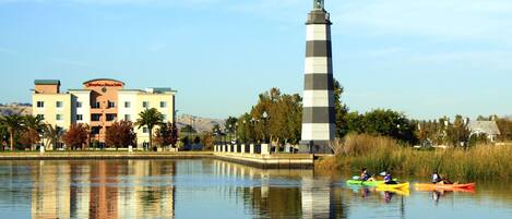 A calm lake with a lighthouse and a building with a sign.