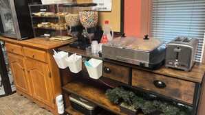 A counter with a coffee machine, cereal containers, a toaster, and a menu board.