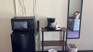 A compact kitchenette with a microwave, coffee maker, and a small trash bin.