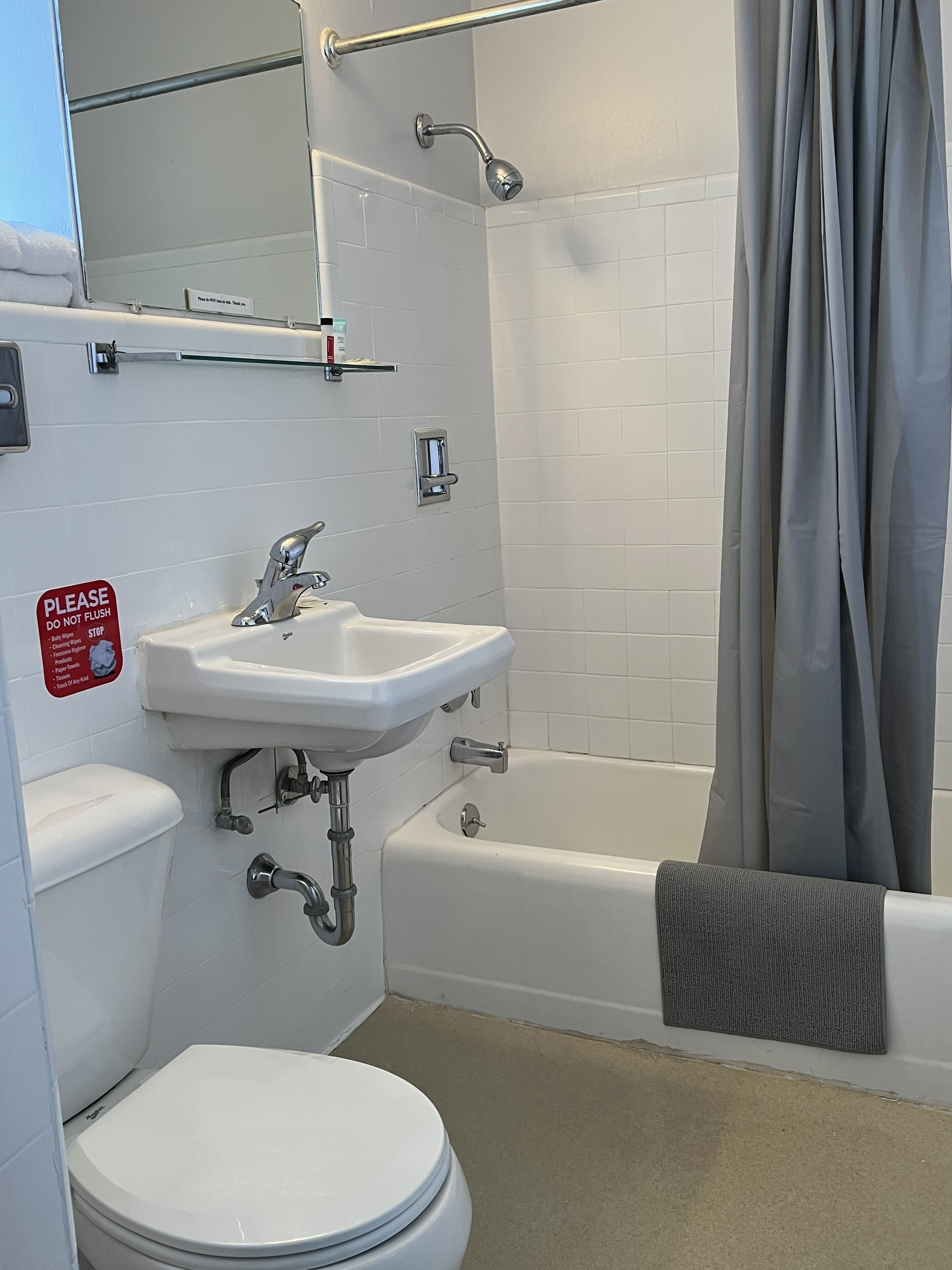 Un bagno con WC bianco, lavandino e vasca. È presente una tenda da doccia e un porta asciugamani.