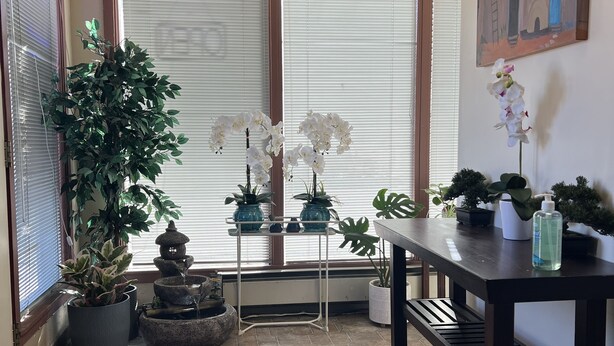 A room with a tiled floor, a table with a bottle, and potted plants.