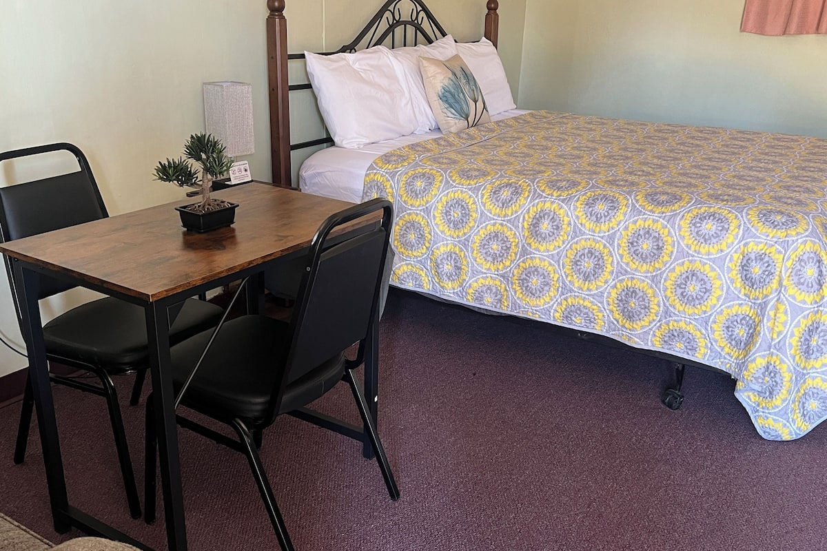 A small room with a bed, a desk, and two chairs.