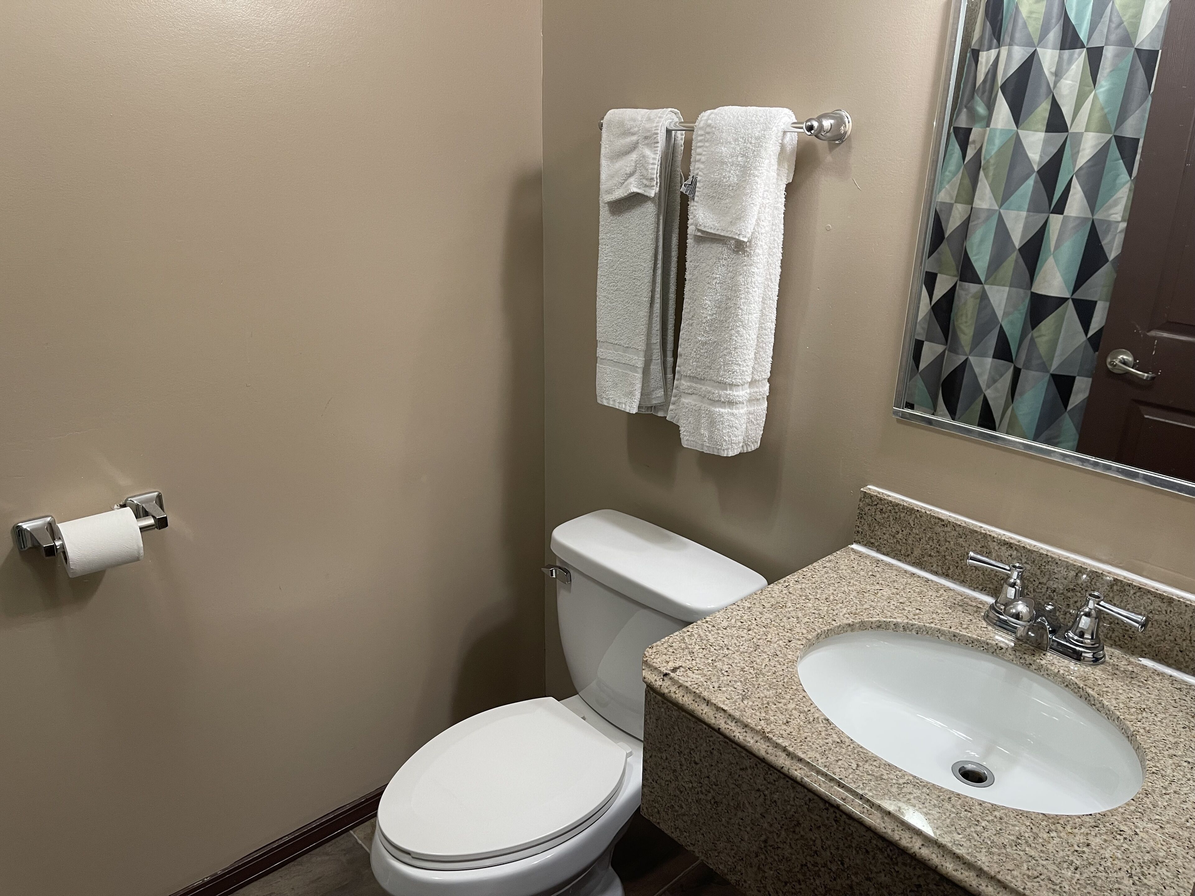 A bathroom with a toilet, sink, and towels.