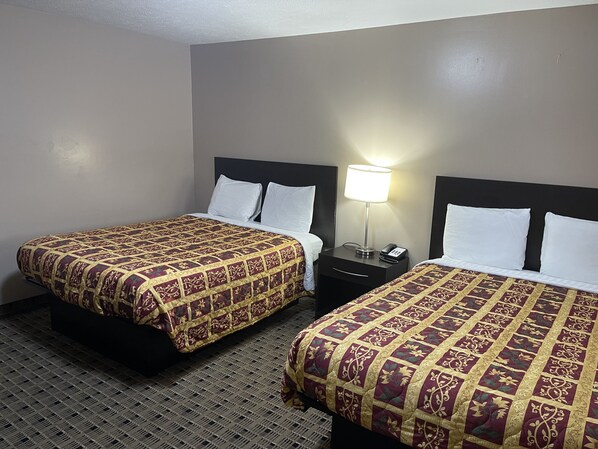 Two single beds with patterned bedding, bedside tables with lamps, and a carpeted floor. - Economy Inn And Suites Ashtabula (Ashtabula)