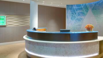 A reception area with a curved reception desk, a digital screen, and a decorative vase.