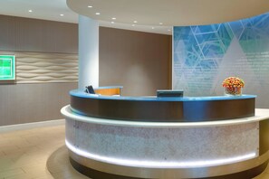 A reception area with a curved reception desk, a digital screen, and a decorative vase.