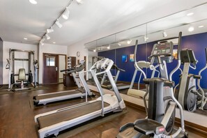 Un gimnàs amb cintes de córrer, el·líptiques i equipament per a musculació.
