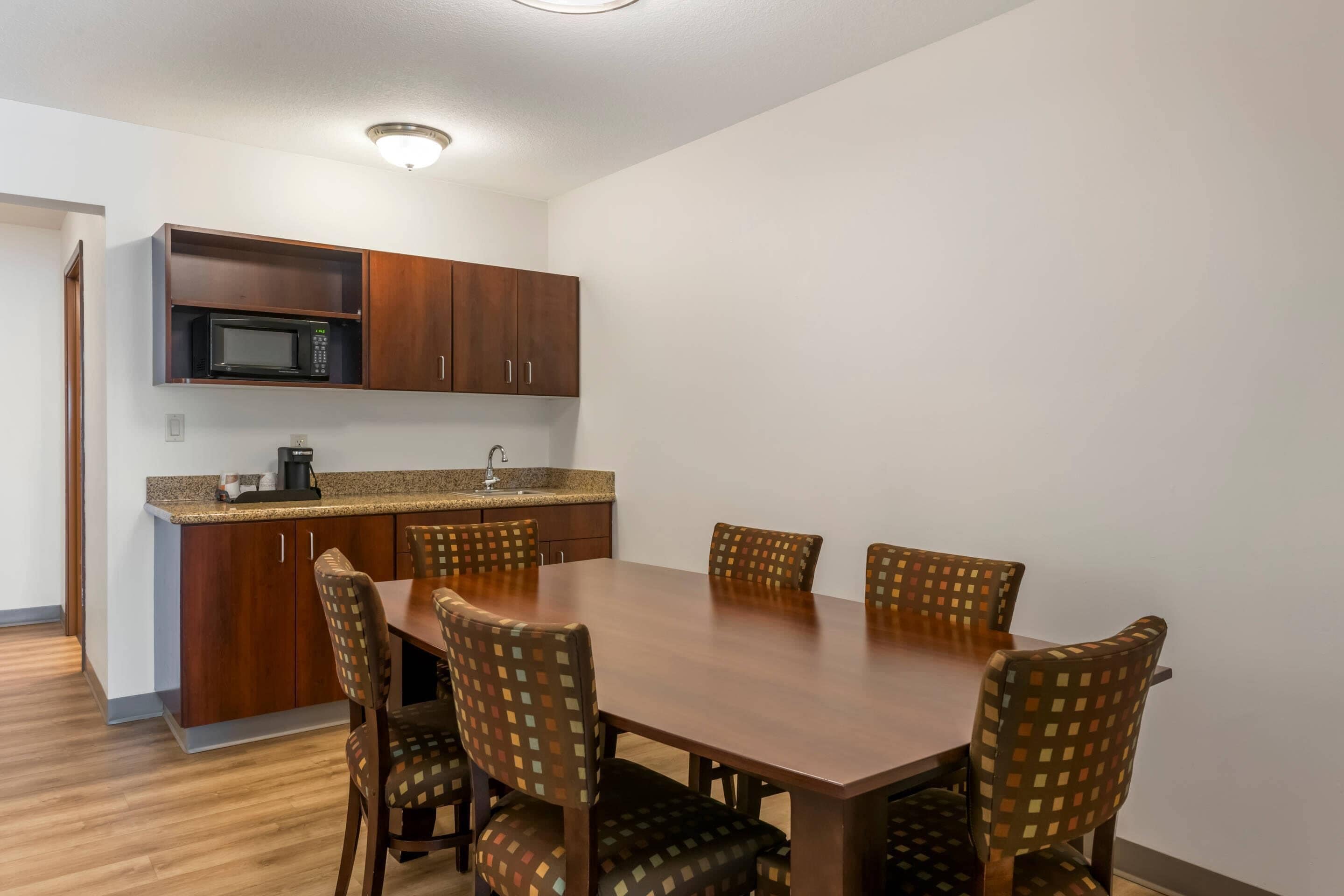 A dining area with a wooden table and chairs, a microwave, and a coffee maker.