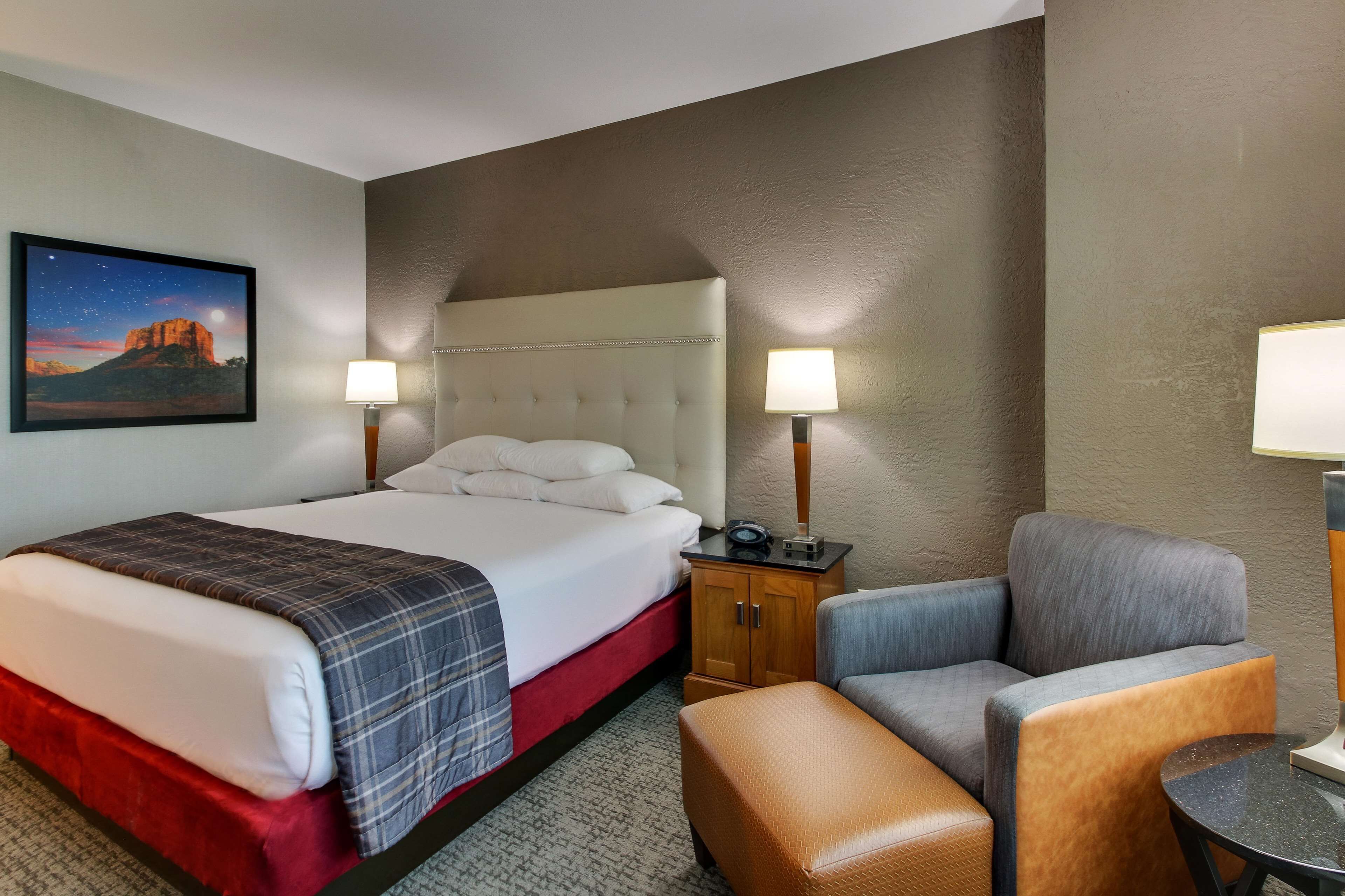 Une chambre d’hôtel avec un grand lit, deux tables de chevet avec des lampes, une petite table et une chaise.