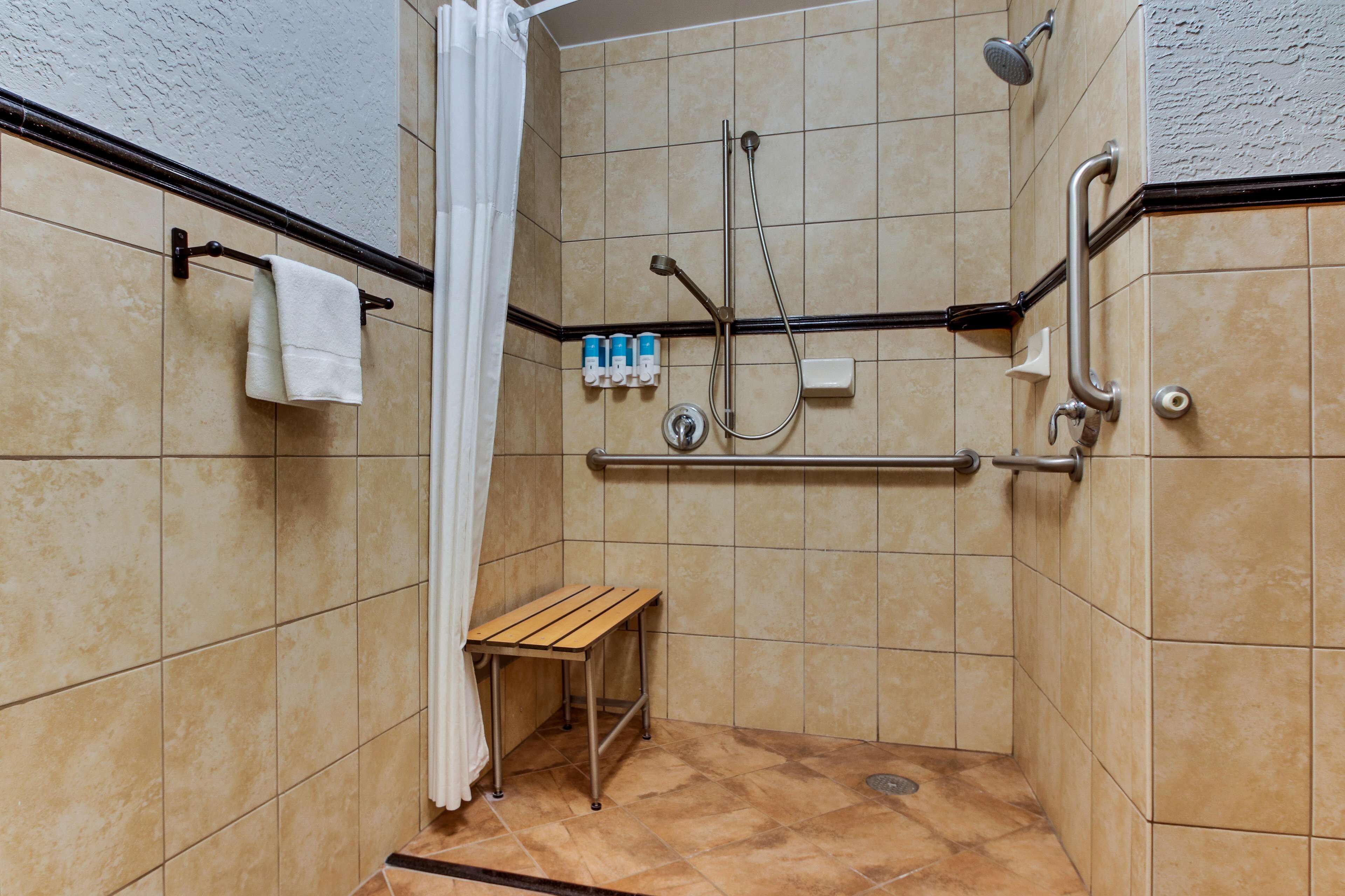 A shower area with a bench, grab bars, and a towel rack.
