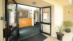 An entrance with a reception desk, a warning sign, and a potted plant. - Ascot Epsom Motel (Auckland)