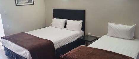 Una habitación de hotel con una cama, una mesita de noche y una lámpara fijada a la pared.