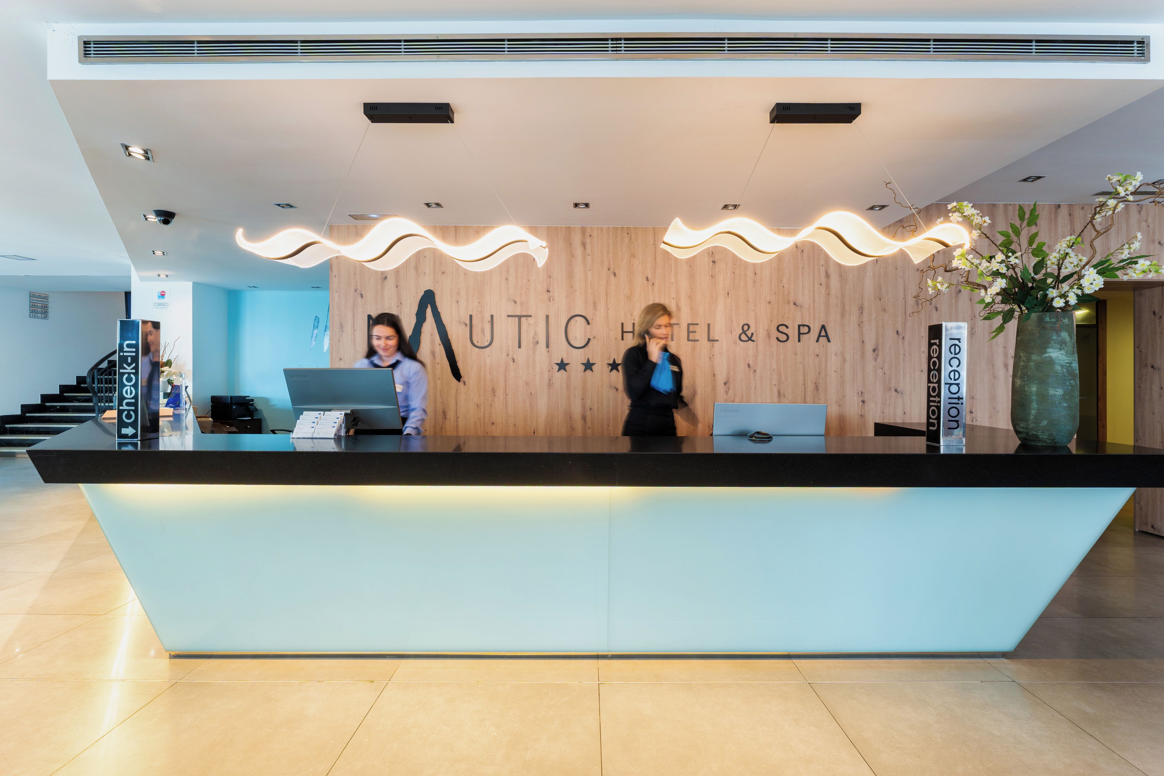 Una recepción con fondo de madera y el texto 'MUTIC HOTEL & SPA'.
