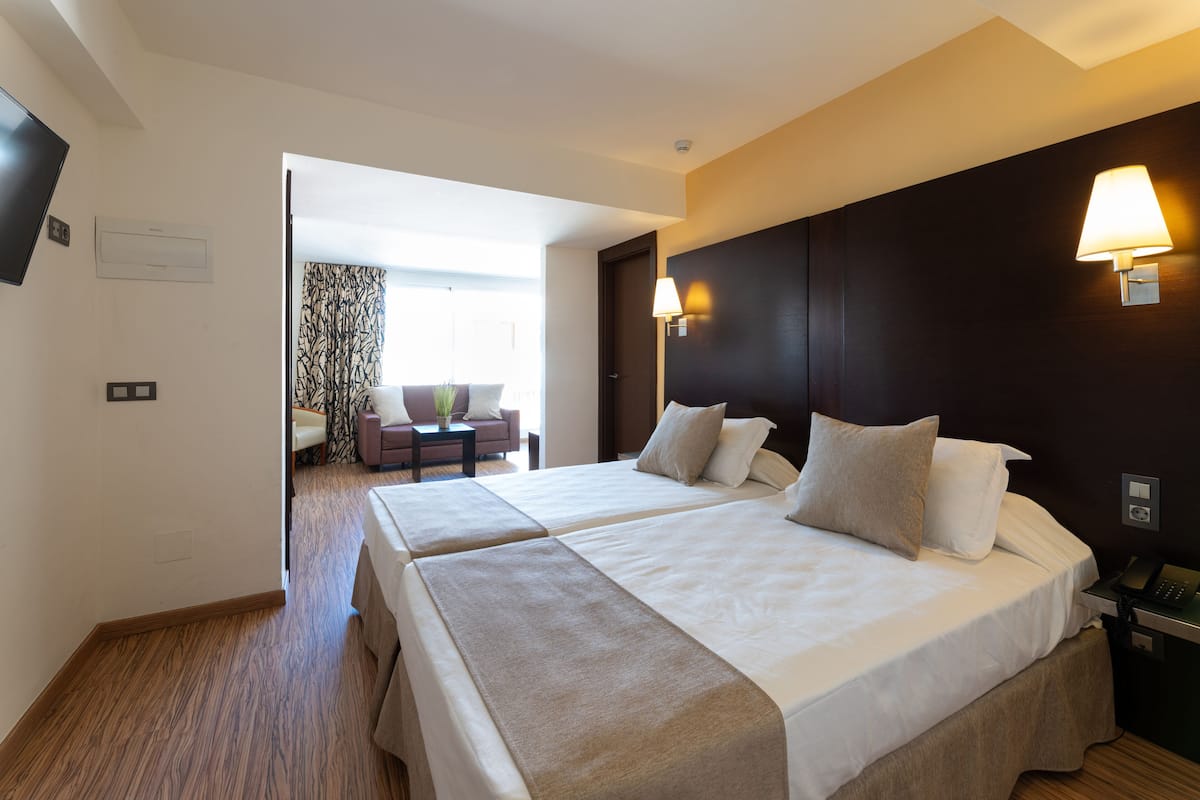 Een hotelkamer met twee bedden, een bureau, een stoel en een lamp.