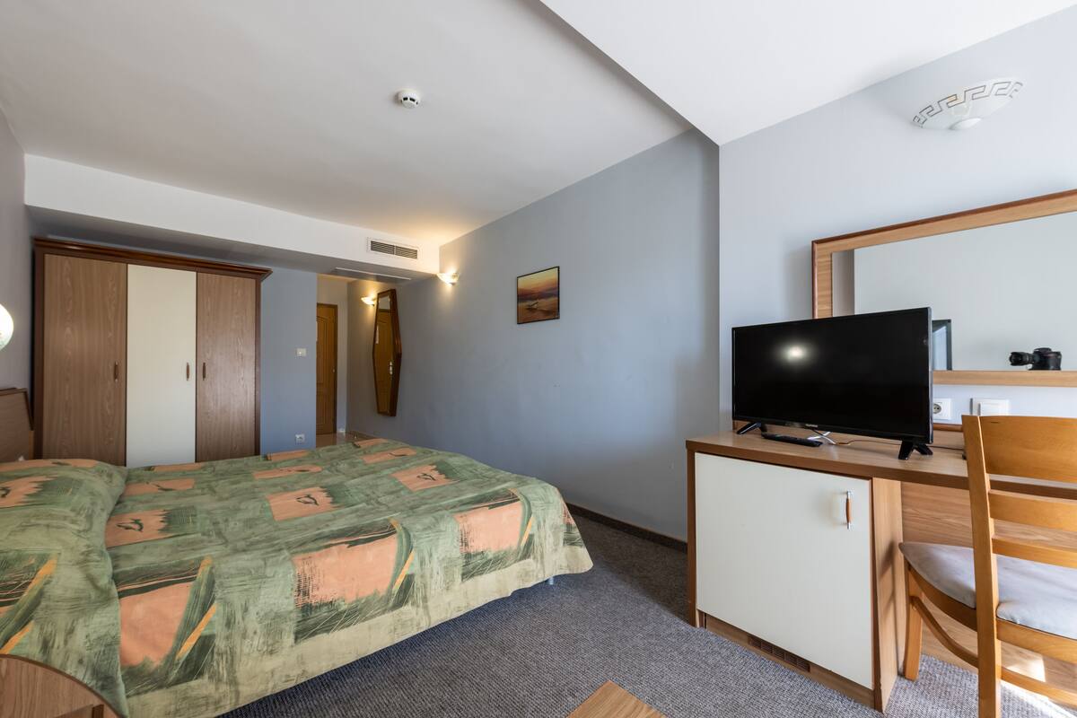 Une chambre à coucher avec un lit, une télévision, un bureau et une armoire.