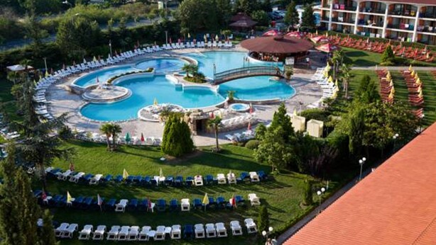 Ein Resort mit einem großen, runden Pool, einer Brücke und einem Gebäude mit rotem Dach.