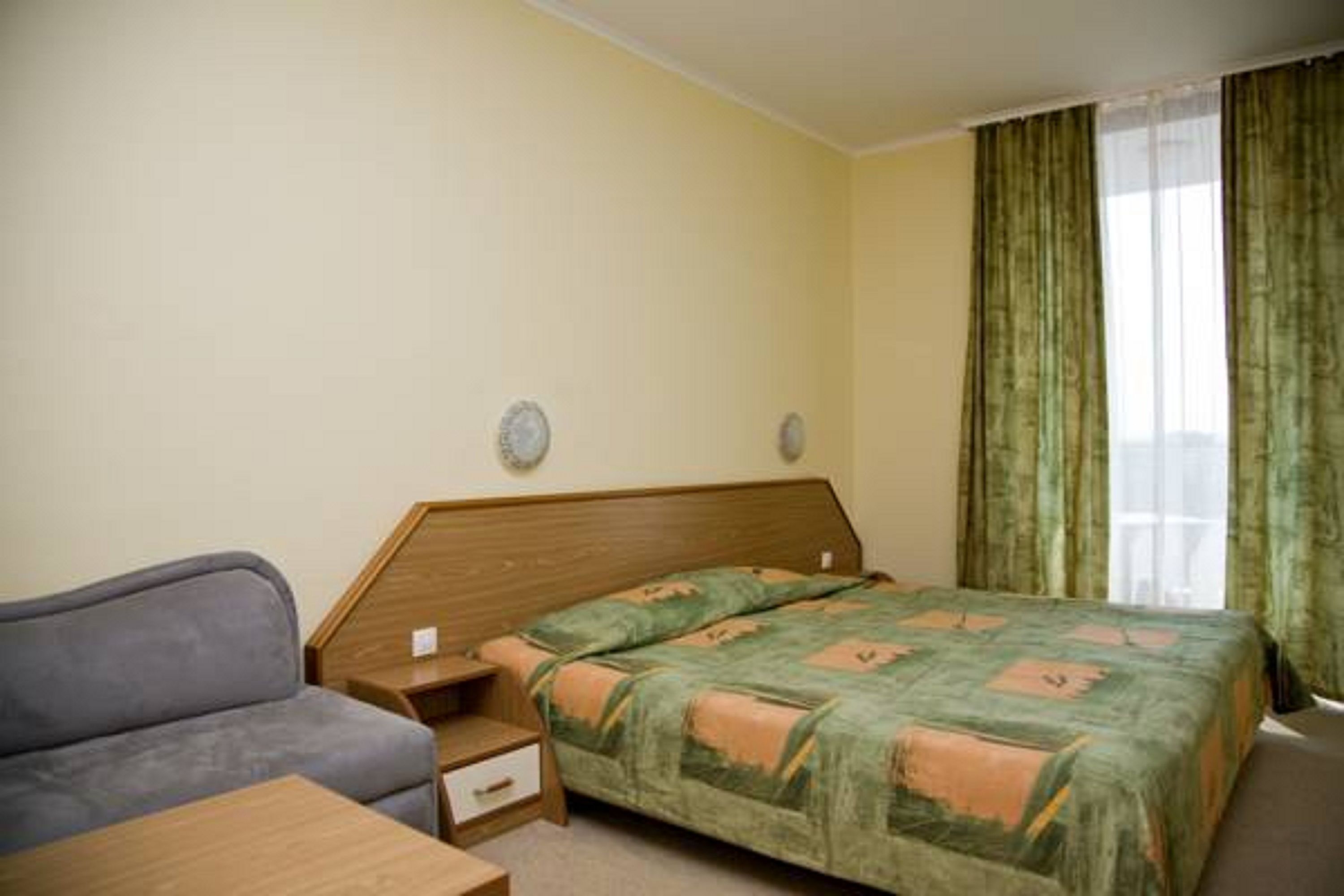 Une chambre d’hôtel avec un lit, un canapé, une table de chevet et une petite table.