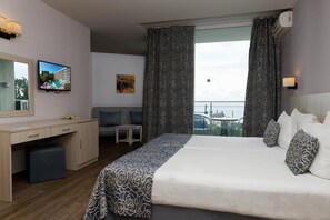 A hotel room with a bed, a desk, a chair, a small table, a balcony with a view, and a TV mounted on the wall. - Slavey (Golden Sands)