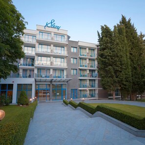 Et hotel med moderne design, flere etager, altaner og et velholdt udendørs område.
