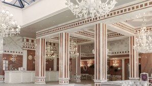 Um lobby luxuoso com tetos altos, lustres e assentos confortáveis.