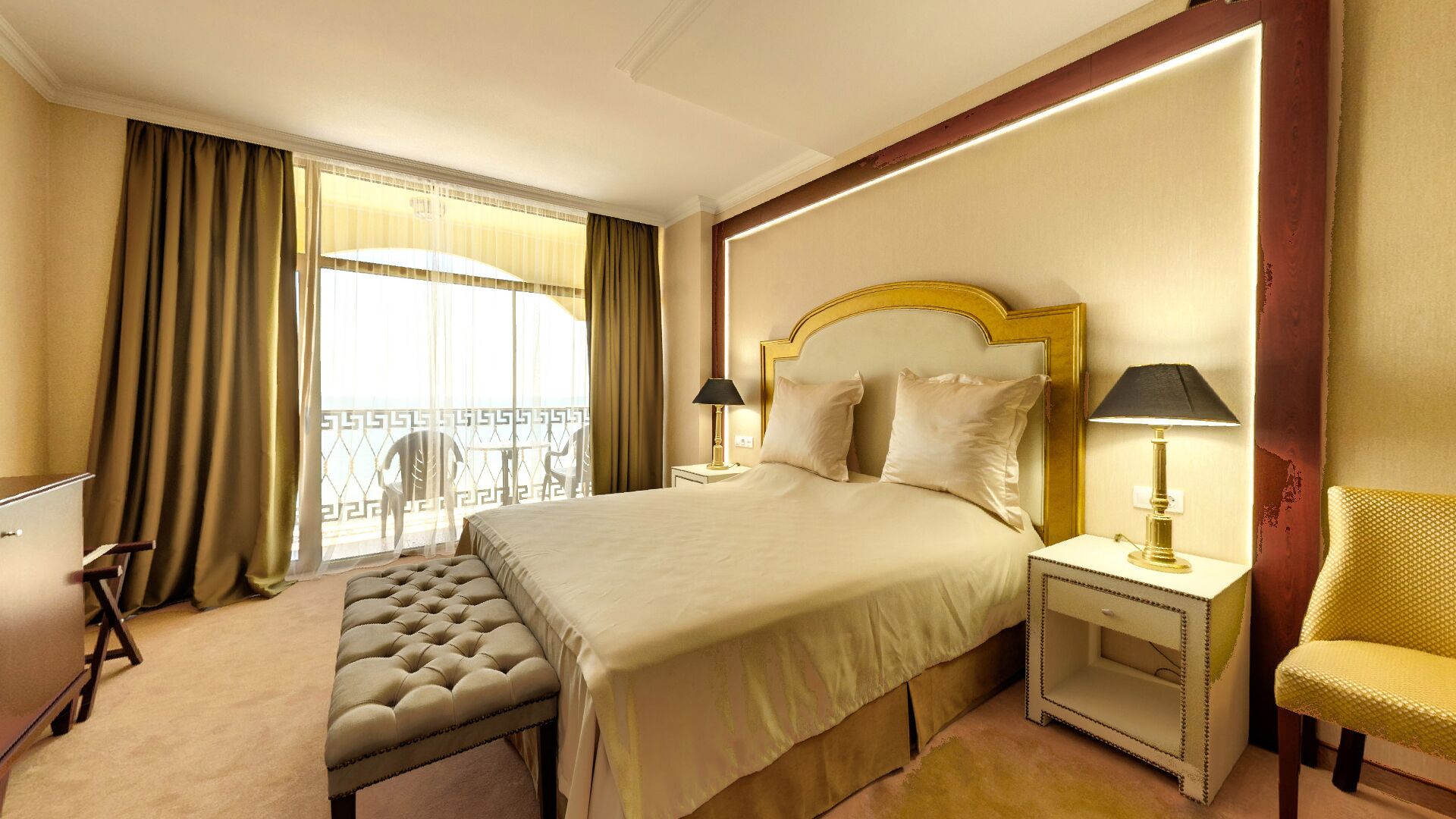 Habitación de hotel con una cama grande, una banca, una silla y un balcón con vistas.