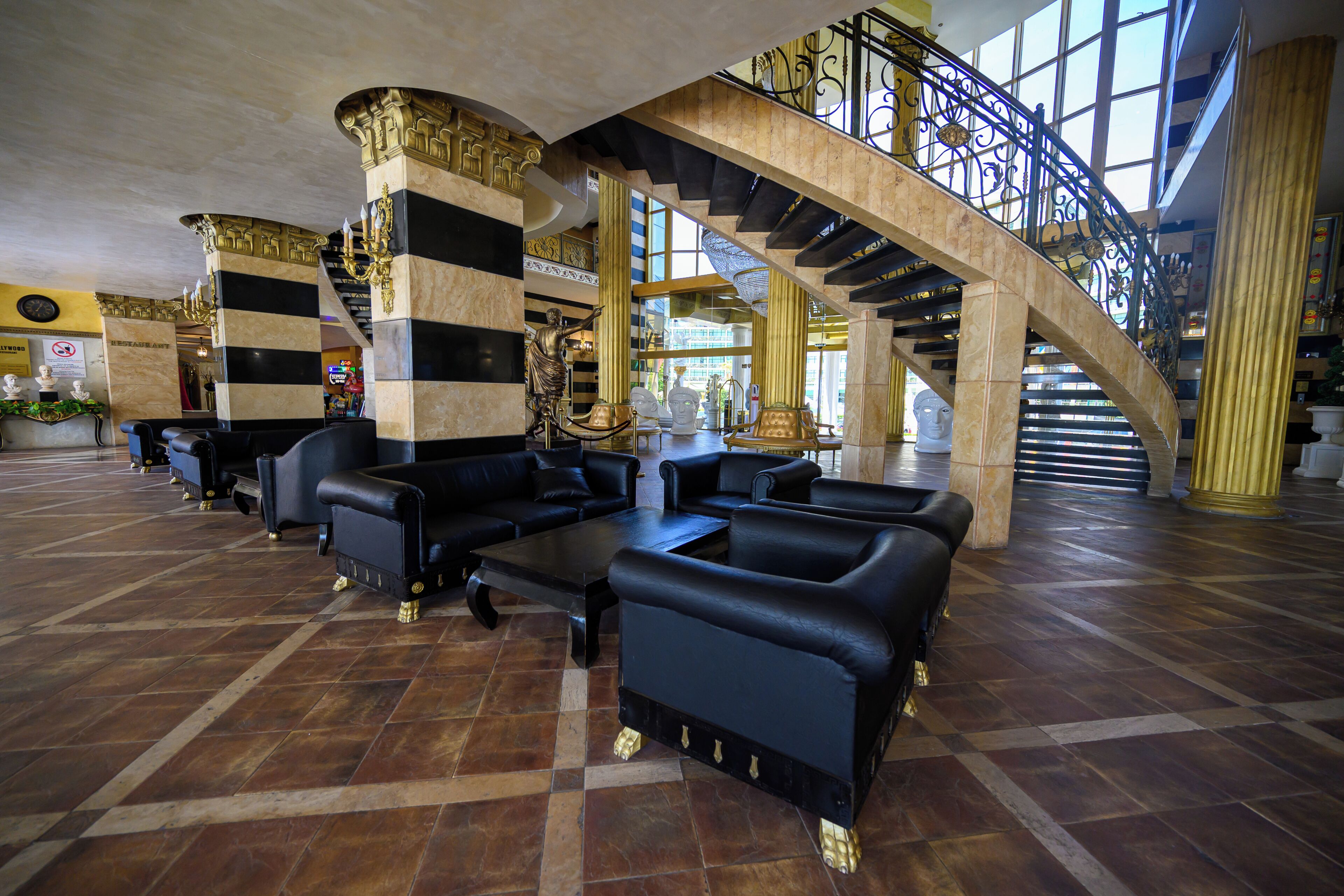 Eine Lobby mit einer imposanten Treppe, Marmorsäulen und Ledersitzgelegenheiten.