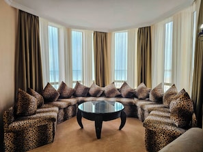 A corner seating area with a glass coffee table, leopard print upholstery, and large windows with sheer curtains.