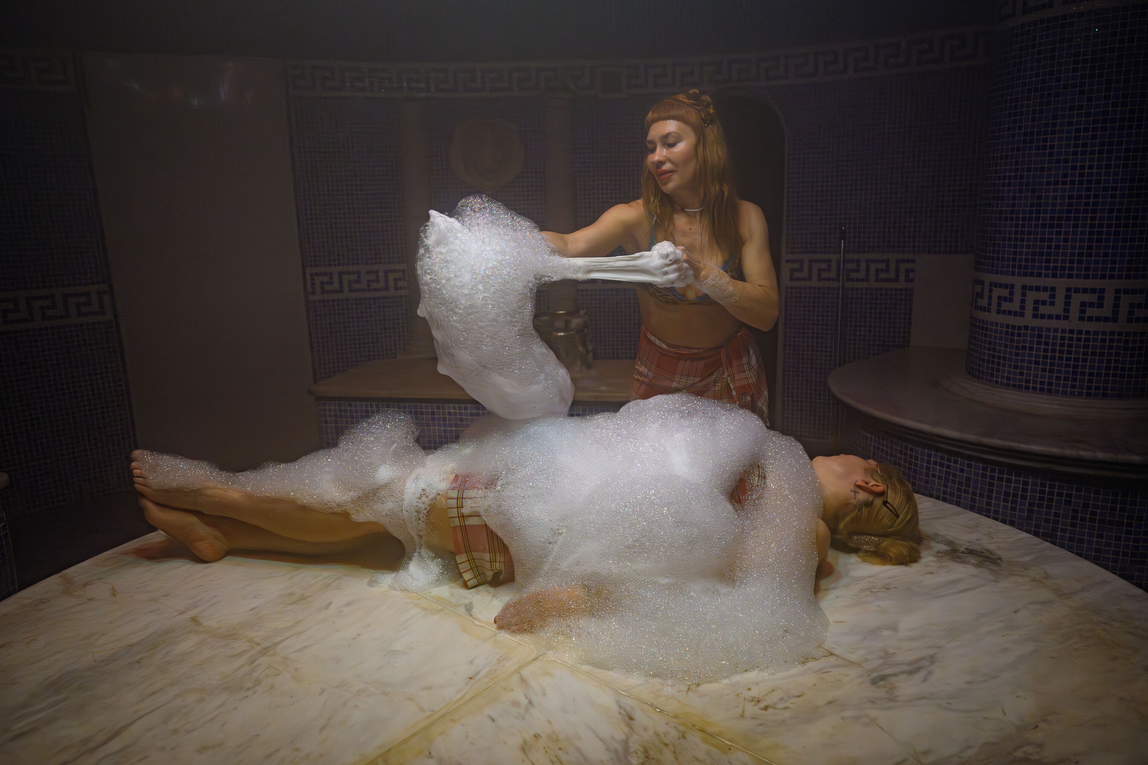 A person lying on a bed with a foamy substance on them.