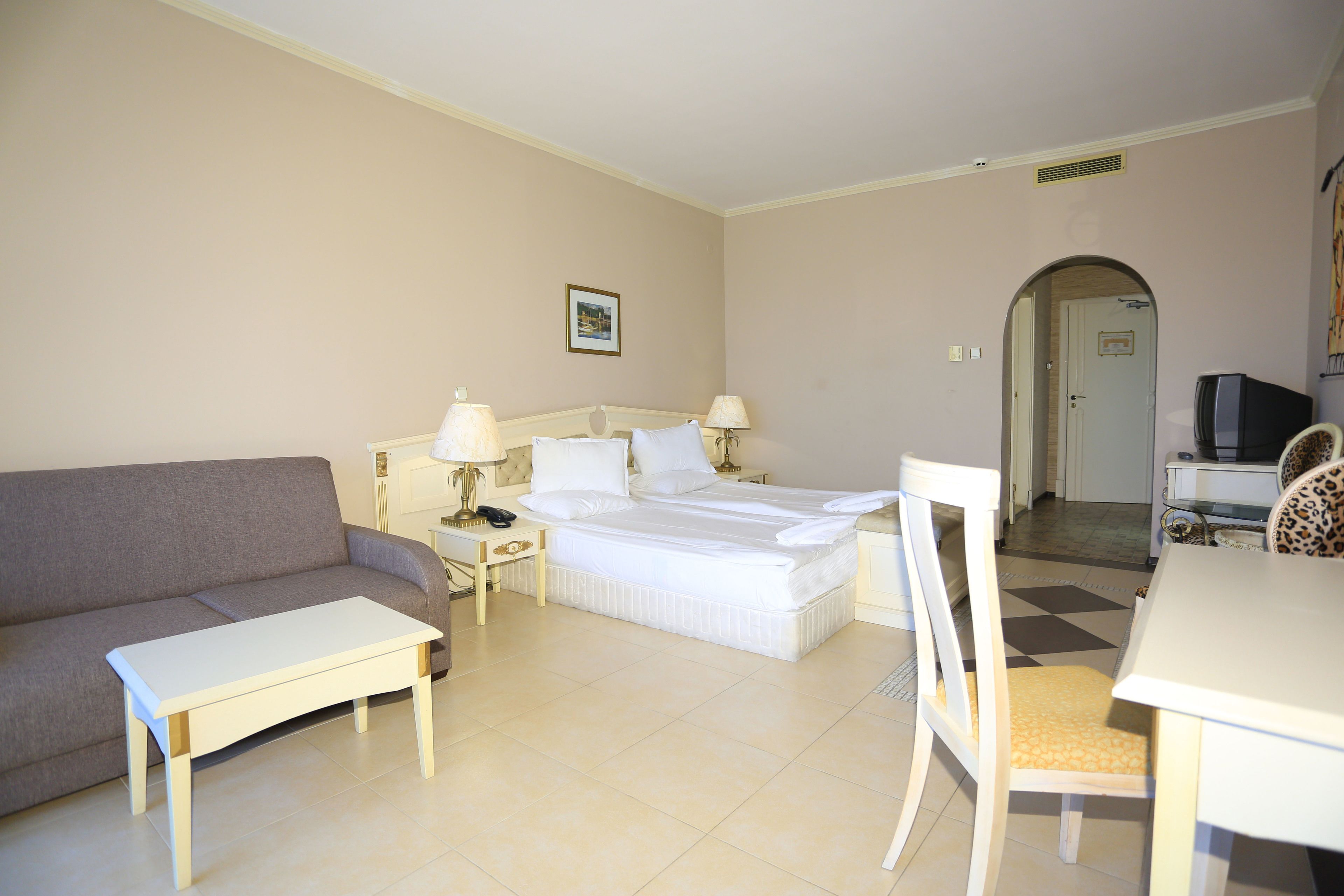 Una habitación de hotel con una cama, un sofá, una mesa de comedor y una silla.