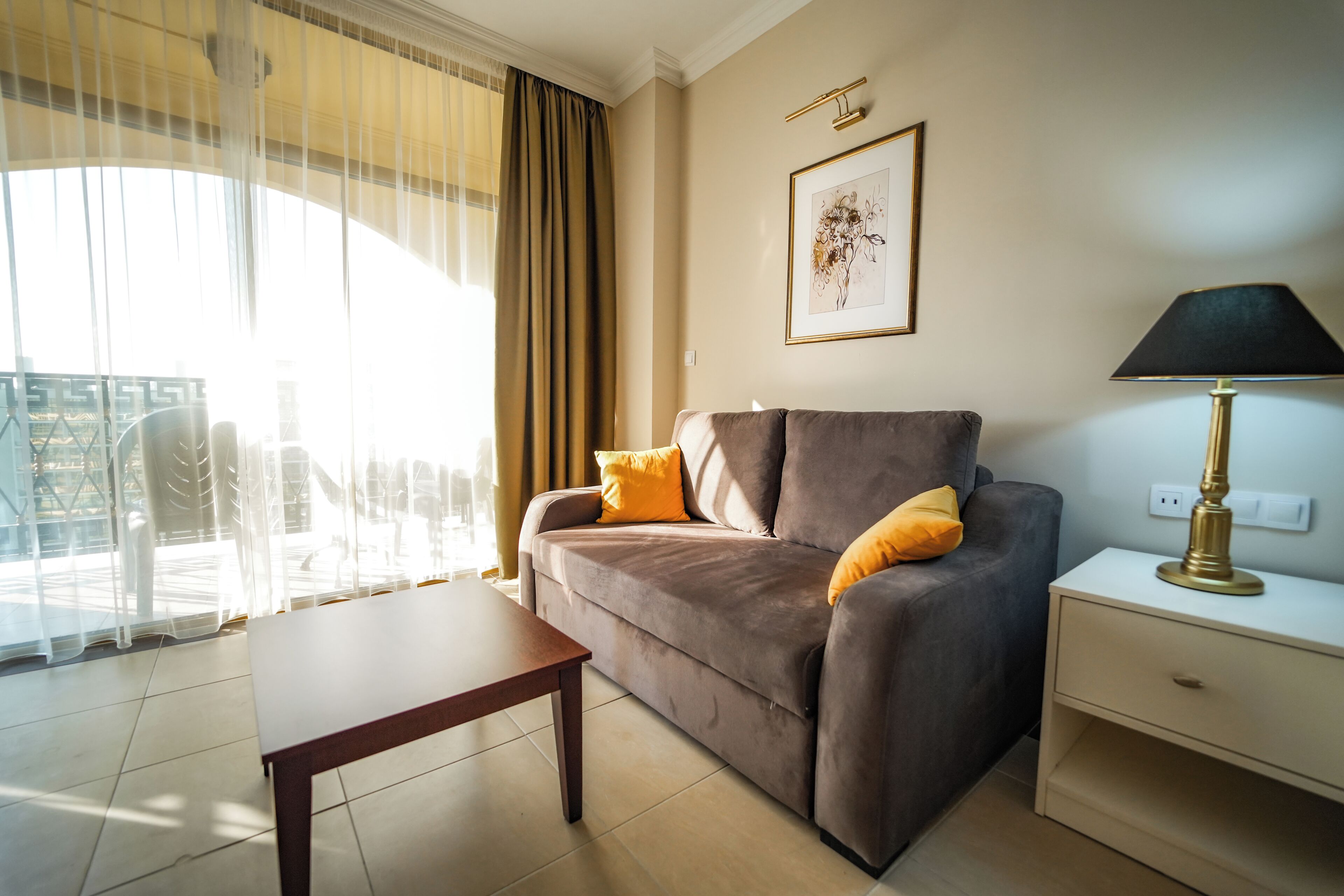 A living room with a sofa, a coffee table, a lamp, and a painting on the wall.