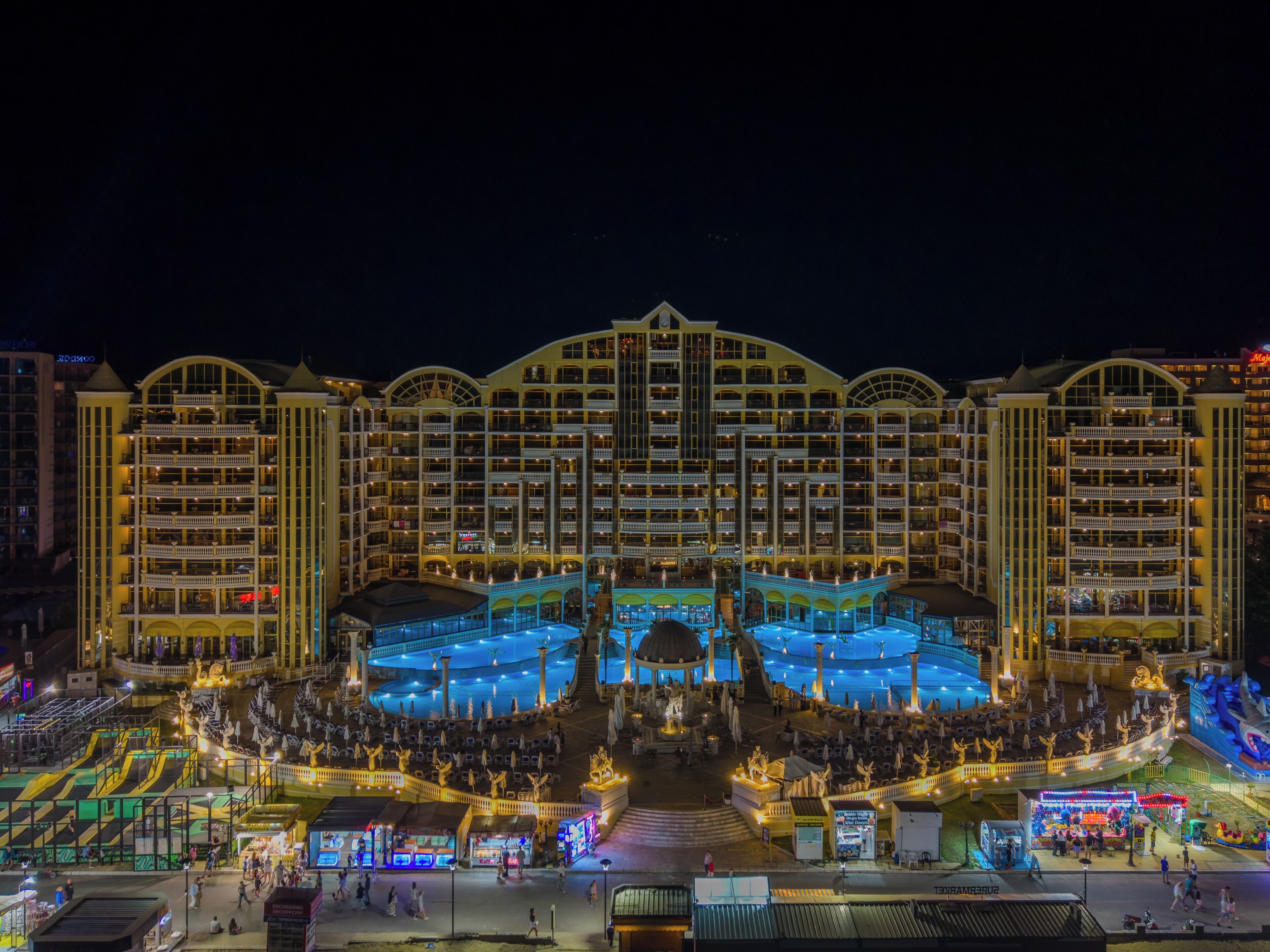 Een meerlaags hotel met balkons, een centrale binnenplaats en een zwembad.