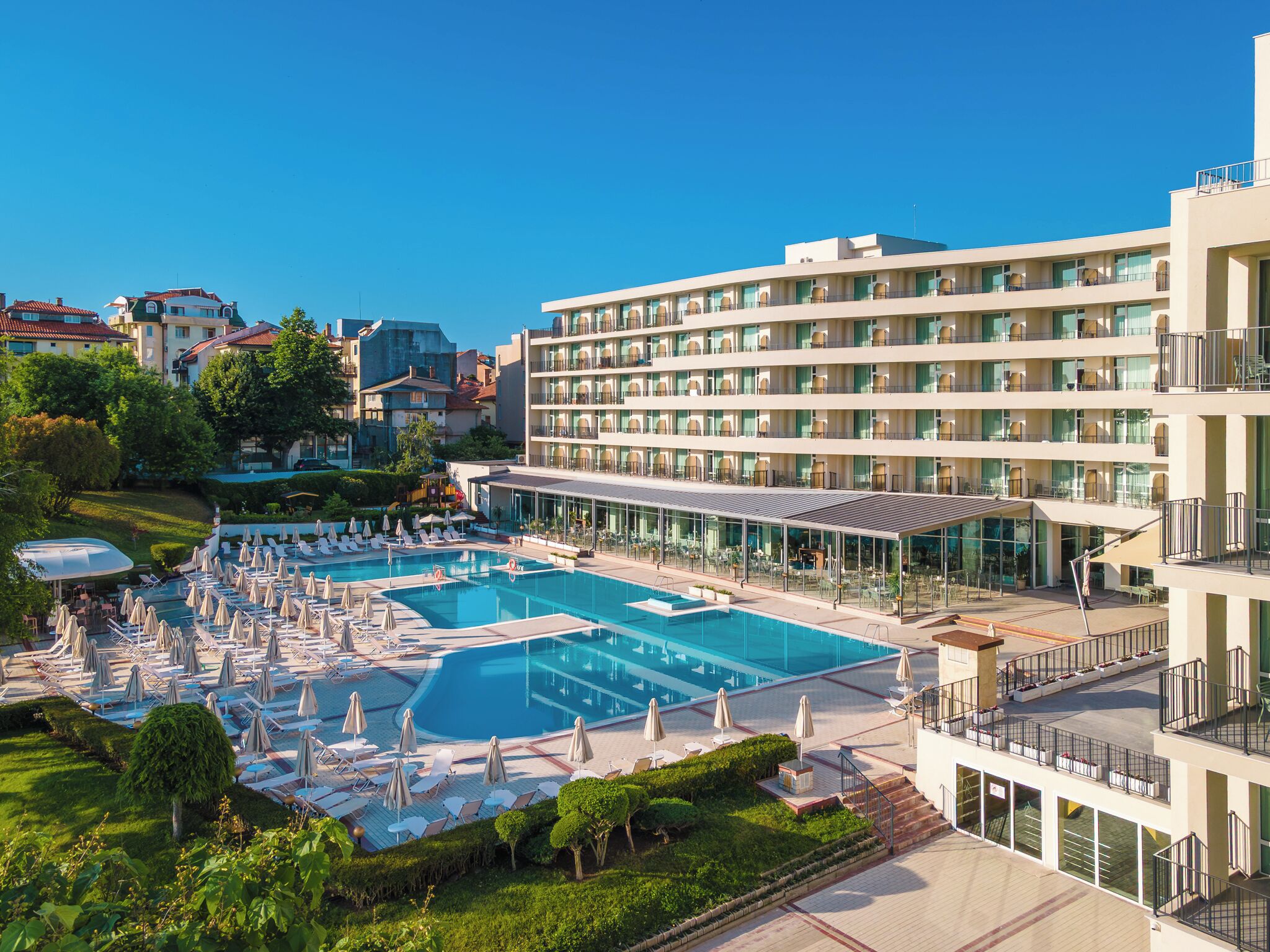 Un hotel con un amplio espacio de piscina, varios balcones y un jardín bien cuidado.