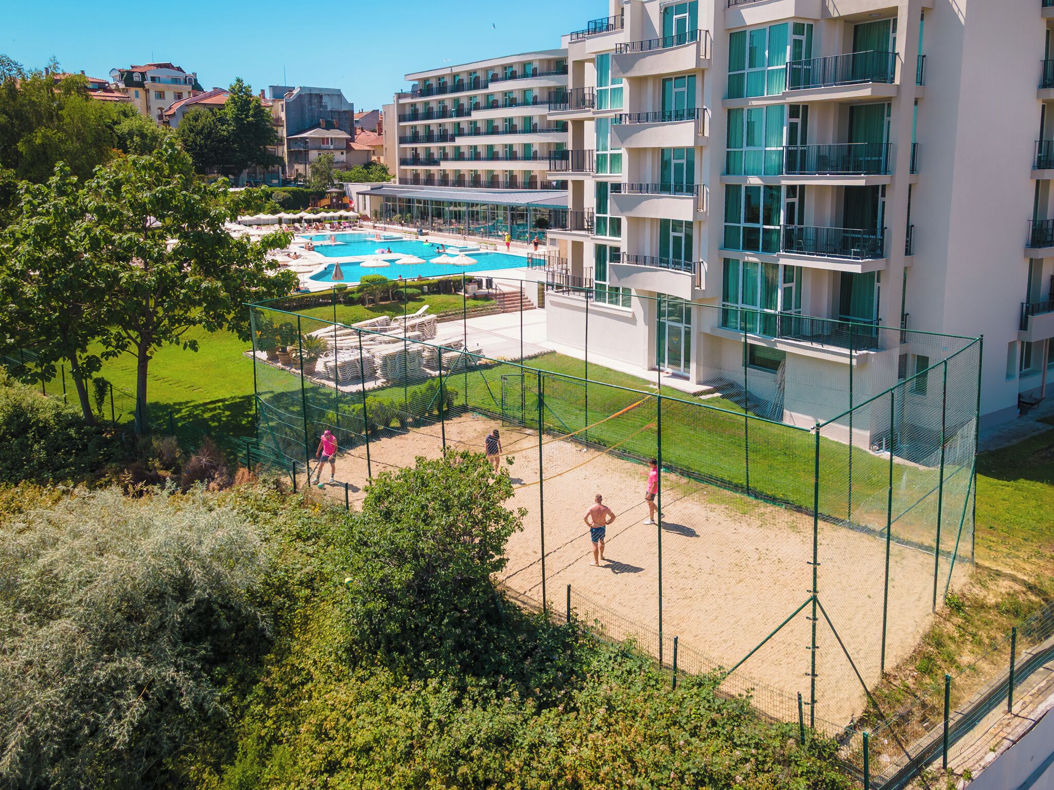 A hotel with a pool, tennis court, and a view of the surrounding area.
