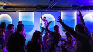 A person addressing an audience in a room with large screens displaying a moonlit scene.