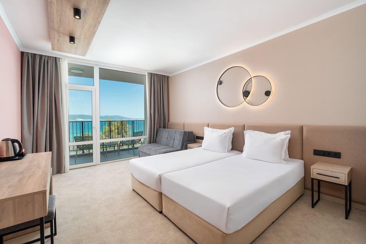 A hotel room with a large bed, a desk, and a view of the outdoors.