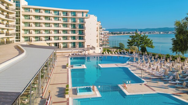 Um hotel com área de piscina, várias varandas e vista para o mar.