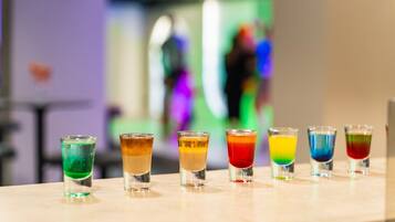A row of colorful shot glasses on a bar counter.