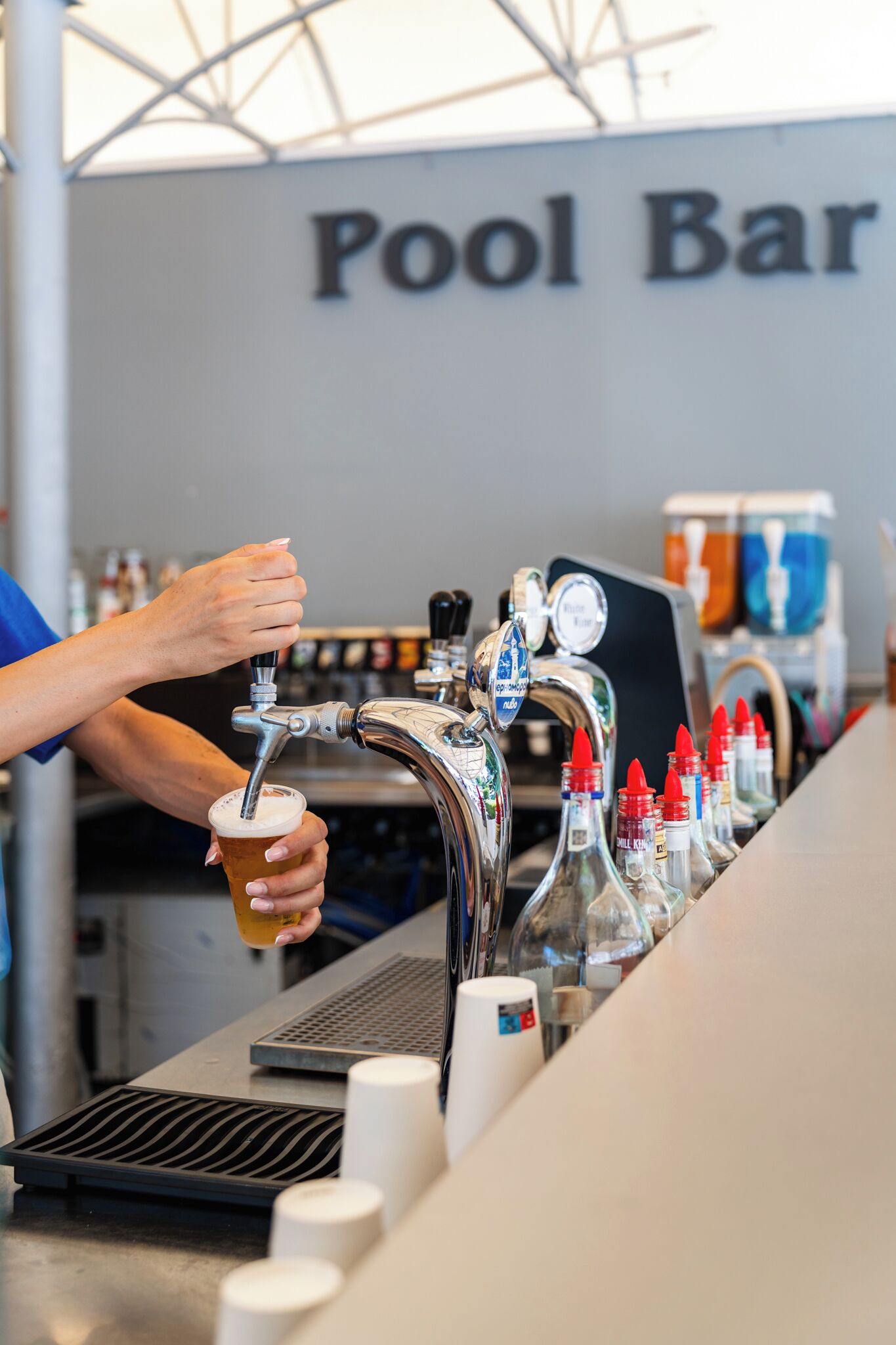 Een bar met een biertappunt en een hand die een biertje vasthoudt.