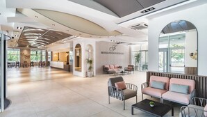 Um hall amplo com balcão de recepção, área de estar e grandes janelas.