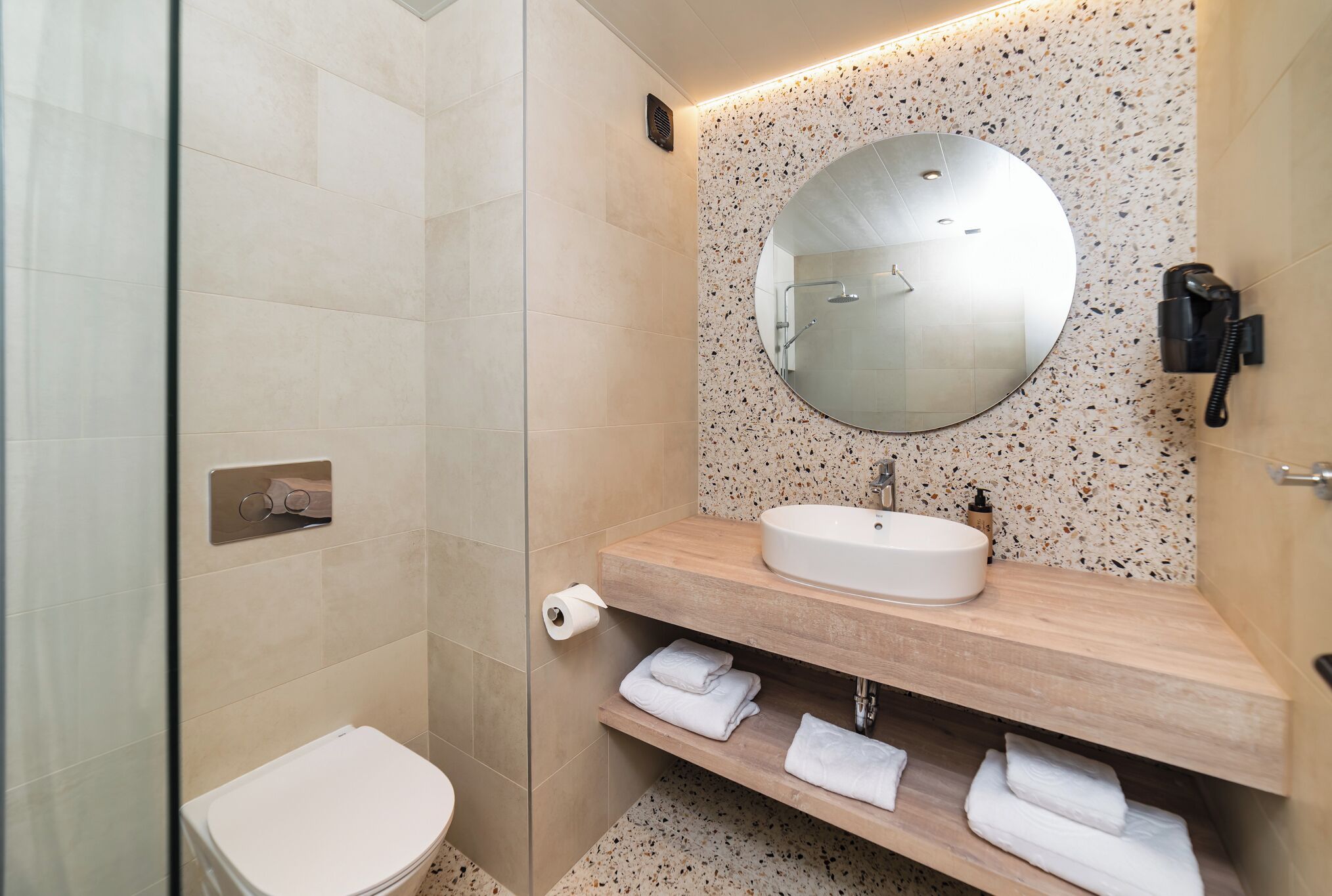Une salle de bain moderne avec des toilettes, un lavabo et un miroir.