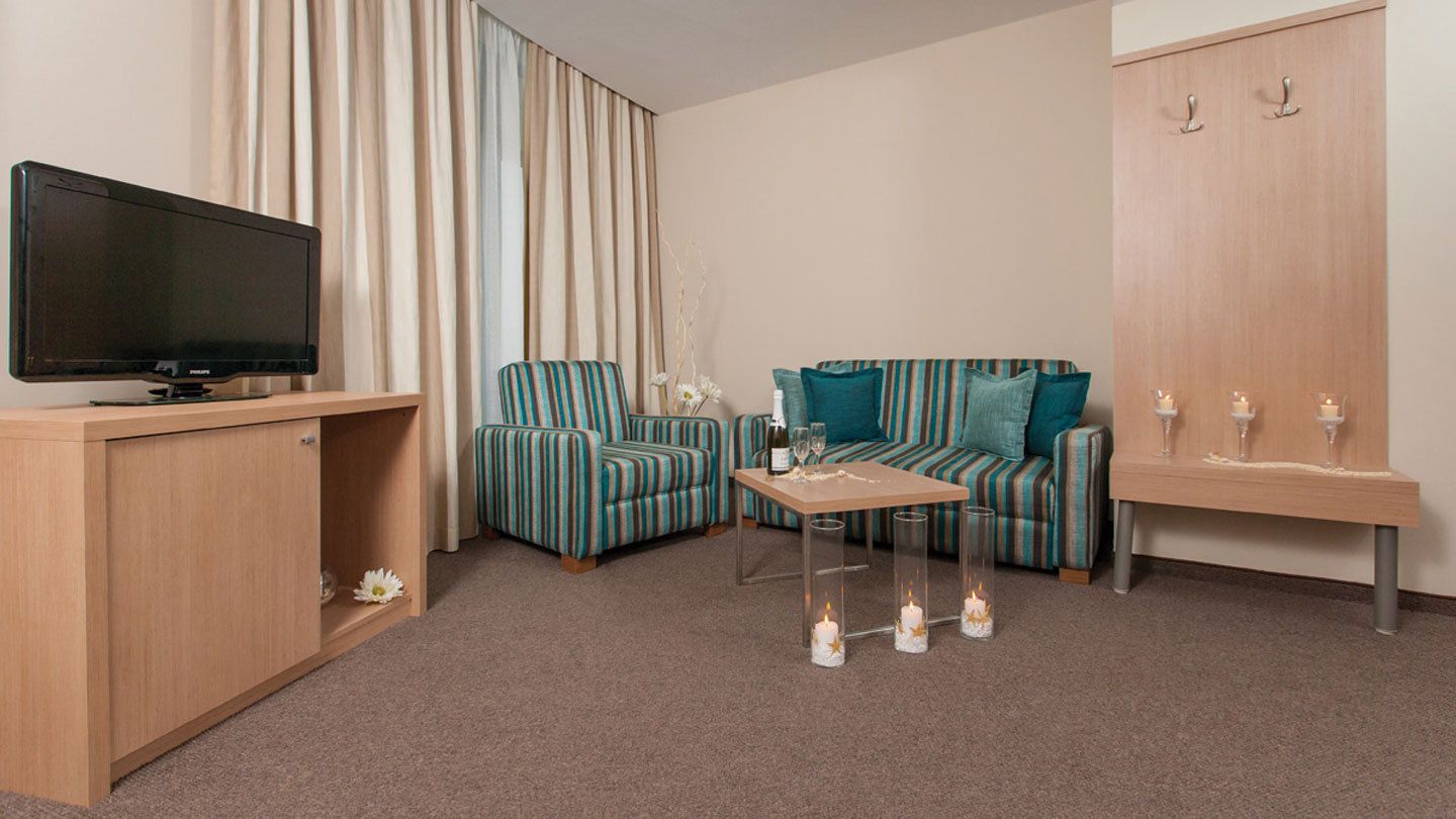Una sala de estar con televisor, sillones a rayas, un sofá, una mesa de centro y un mueble de madera.