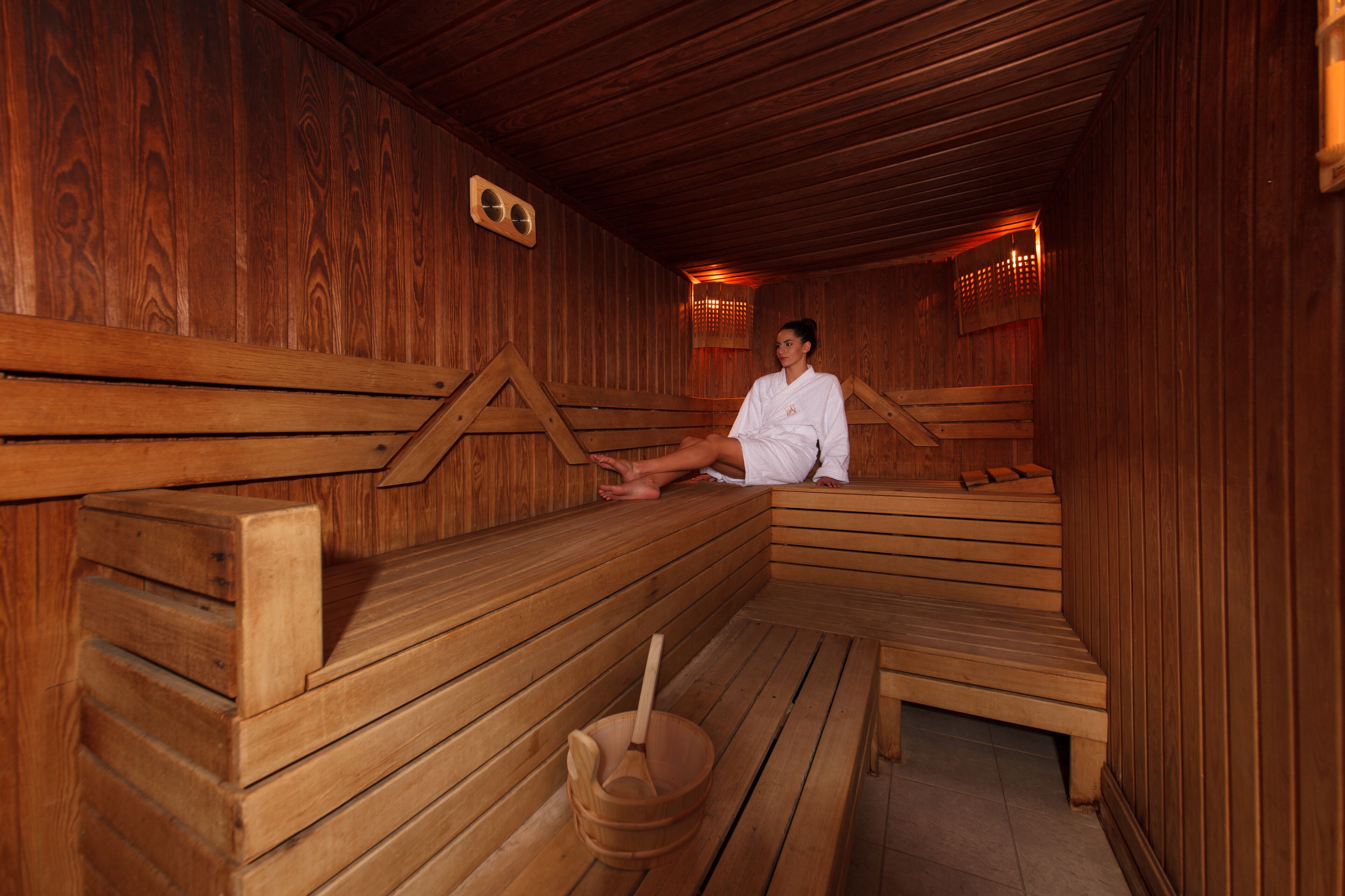 A wooden sauna with benches and a wooden bucket.