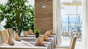 A dining area with tables set for a meal, a potted plant, and a view of the outdoors. - Azalia Hotel Balneo & SPA (Varna)