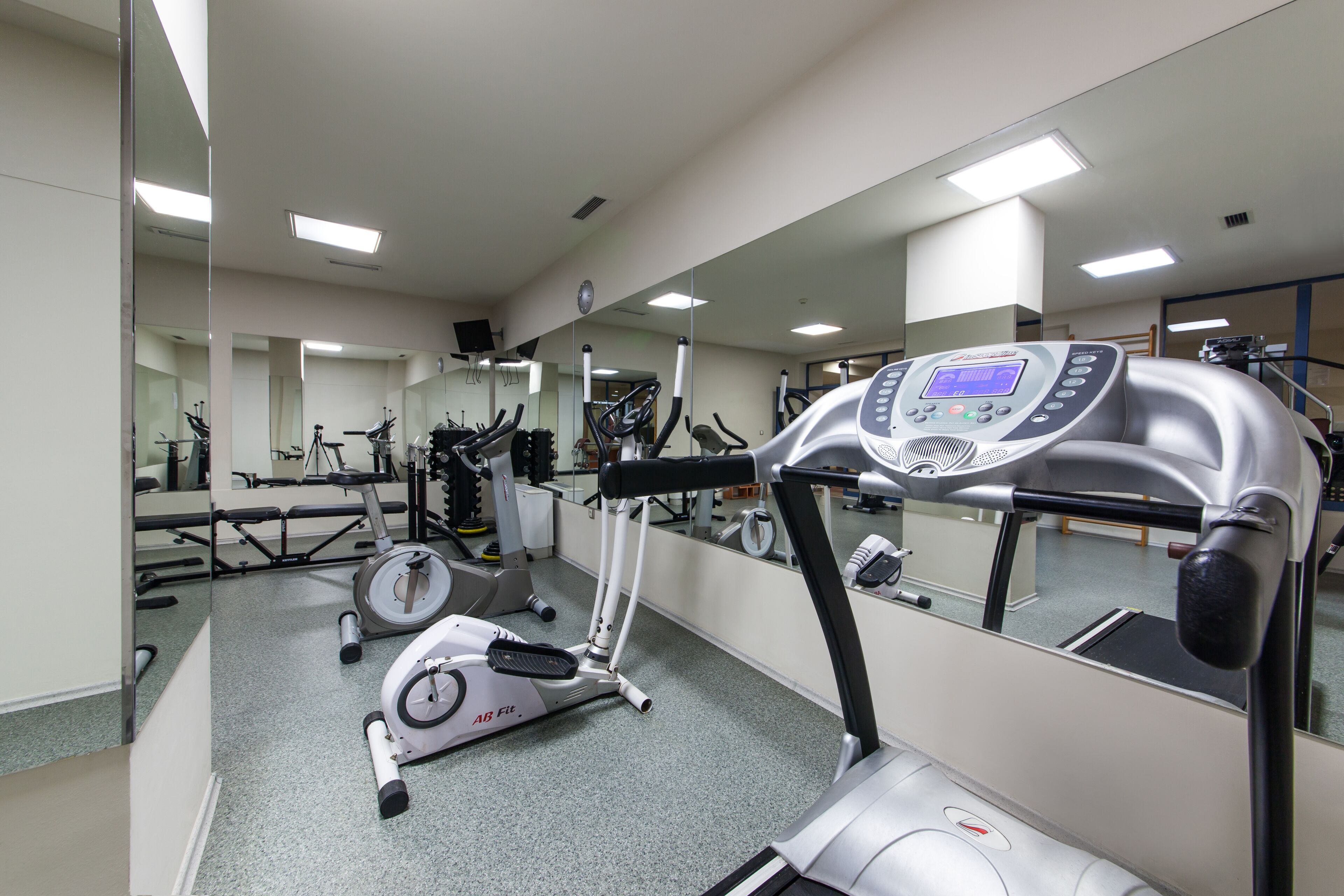 Un gimnasio con equipo de ejercicio, un espejo grande y una cinta de correr.
