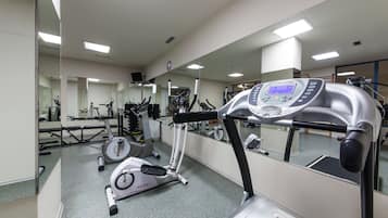 Un gimnasio con equipo de ejercicio, un espejo grande y una cinta de correr.