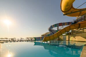 A swimming pool with a water slide, lounge chairs, and umbrellas. - Azalia Hotel Balneo & SPA (Varna)
